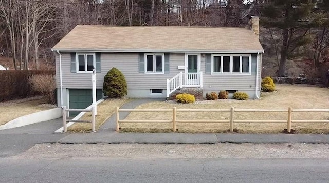 view of front facade with a fenced front yard, driveway, an attached garage, and a chimney