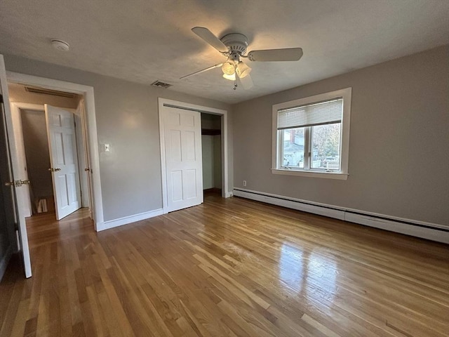 unfurnished bedroom with visible vents, baseboards, wood finished floors, a closet, and a baseboard radiator