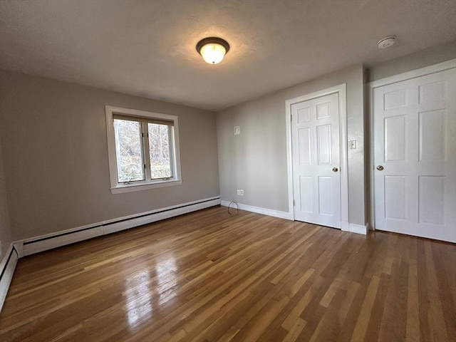 unfurnished bedroom with dark wood finished floors, a closet, baseboards, and baseboard heating