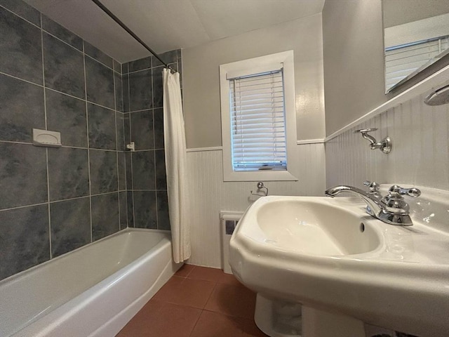 bathroom featuring tile patterned floors, a wainscoted wall, shower / tub combo, and a sink