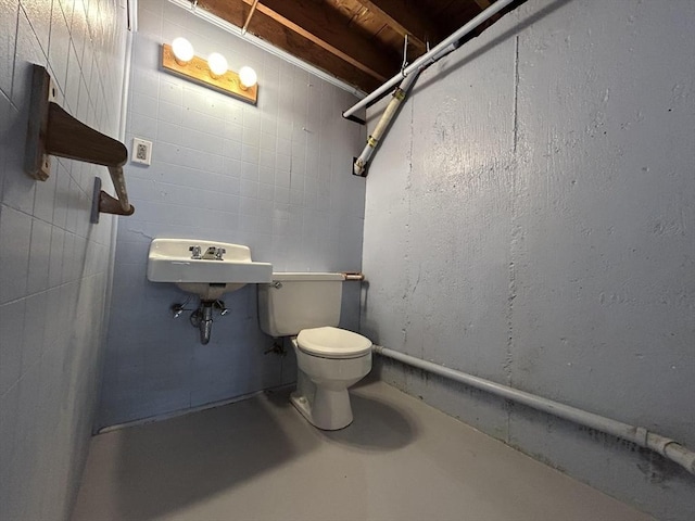 half bathroom with toilet, concrete flooring, and a sink