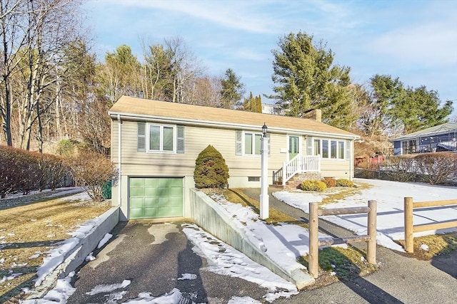 view of front of house featuring aphalt driveway, an attached garage, fence, and a chimney