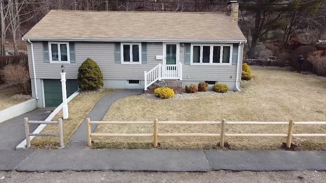 view of front of property with aphalt driveway, a fenced front yard, a chimney, and a garage