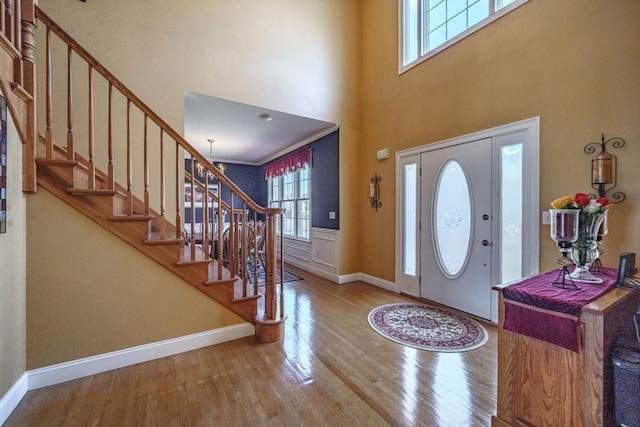 entryway featuring a high ceiling, stairway, wood finished floors, and baseboards