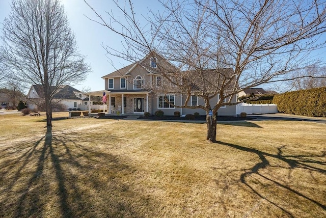 view of front of house with stone siding, a porch, a front lawn, and fence