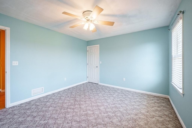 empty room featuring visible vents, baseboards, a healthy amount of sunlight, and carpet flooring