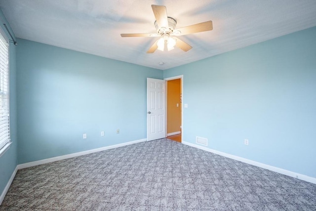 carpeted empty room with visible vents, baseboards, and a ceiling fan