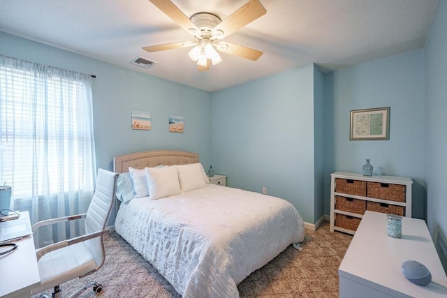 carpeted bedroom with visible vents, multiple windows, baseboards, and a ceiling fan