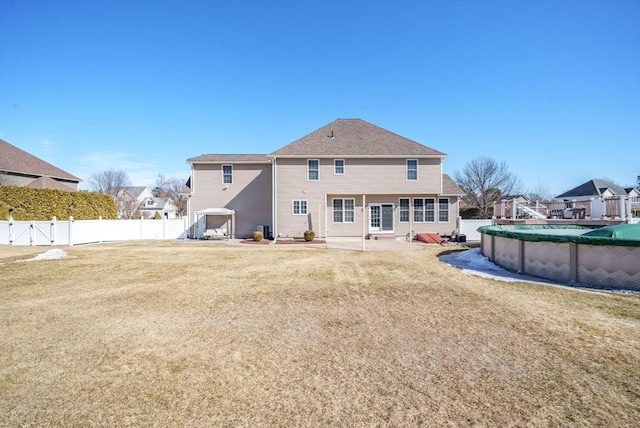 rear view of property with a yard, a fenced in pool, a fenced backyard, and a gate