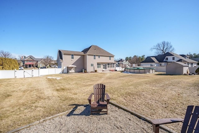 view of yard with a fenced in pool, a residential view, a fenced backyard, a storage unit, and a gate