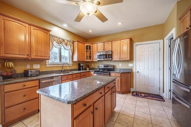 kitchen featuring a sink, dark stone countertops, a kitchen island, stainless steel appliances, and light tile patterned floors