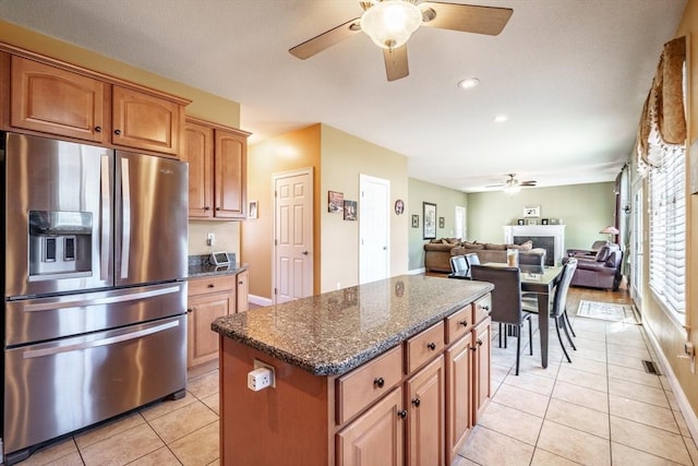 kitchen featuring light tile patterned flooring, dark stone countertops, a center island, and stainless steel fridge with ice dispenser