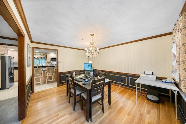 89 Gray St, North Andover, MA 01845 - dining area featuring a chandelier, light wood-style floors, ornamental molding, a wainscoted wall, and a textured ceiling