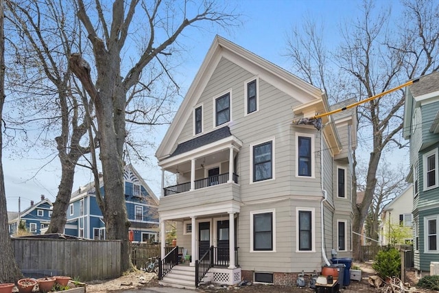view of front of house with central AC, fence, and a balcony