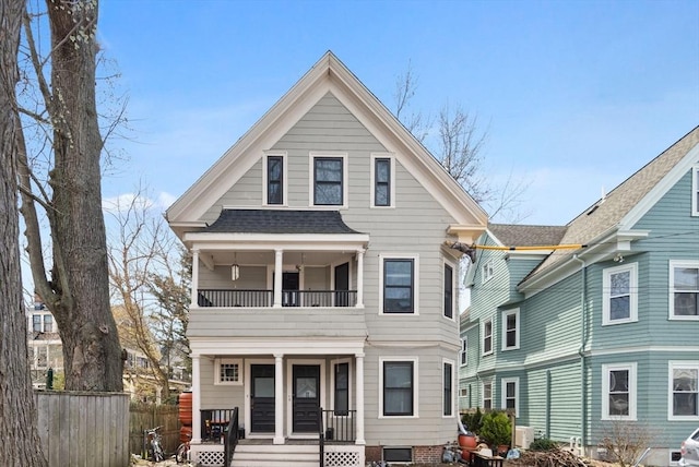view of front of house featuring a porch, fence, a balcony, and roof with shingles
