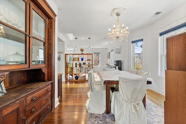 dining space with baseboards, a chandelier, visible vents, and dark wood-type flooring