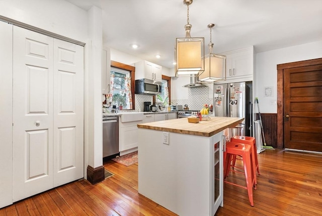 kitchen featuring white cabinetry, hardwood / wood-style flooring, a sink, wood counters, and appliances with stainless steel finishes
