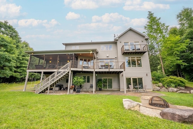 rear view of house featuring a deck, a lawn, a patio, and an outdoor fire pit