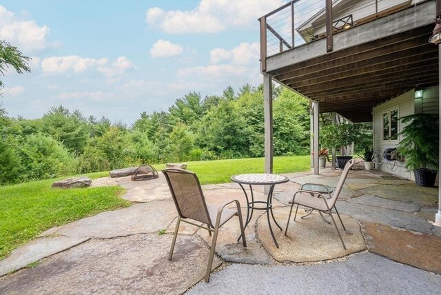 rear view of property featuring a patio, a yard, a deck, and an outdoor fire pit