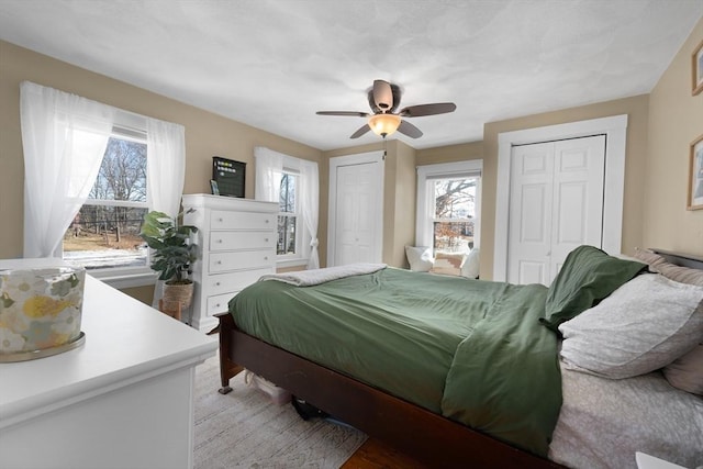 bedroom with ceiling fan and two closets