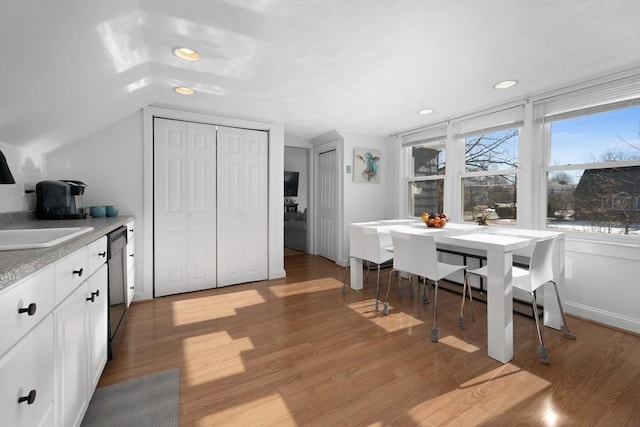 dining space featuring lofted ceiling, sink, and light hardwood / wood-style flooring