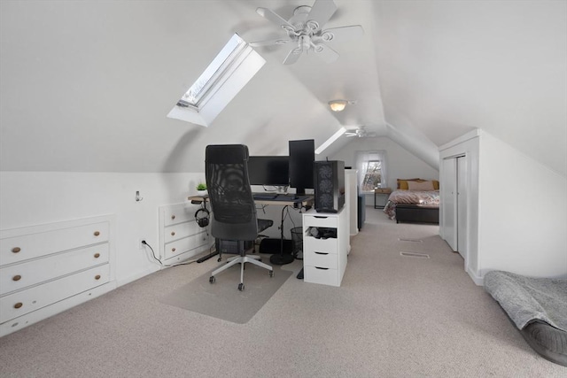 home office featuring ceiling fan, lofted ceiling with skylight, and light carpet