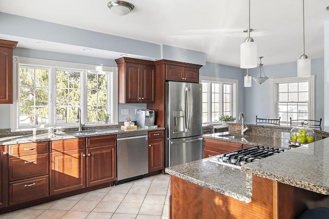 kitchen with light tile patterned floors, dark stone countertops, appliances with stainless steel finishes, and a sink