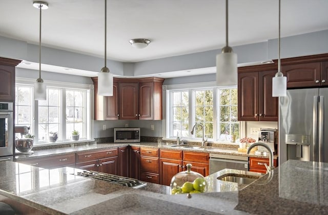 kitchen featuring stainless steel appliances, plenty of natural light, decorative light fixtures, and a sink