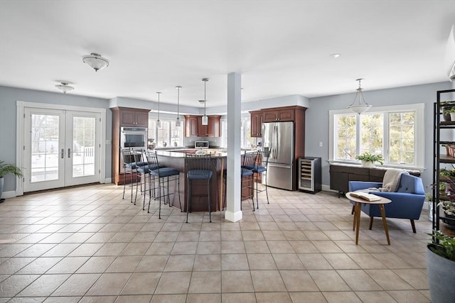 kitchen with french doors, stainless steel appliances, light tile patterned flooring, a healthy amount of sunlight, and a kitchen breakfast bar