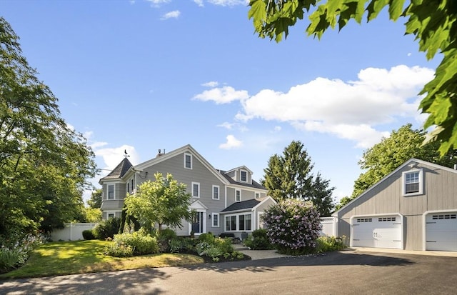 shingle-style home featuring a front lawn and fence