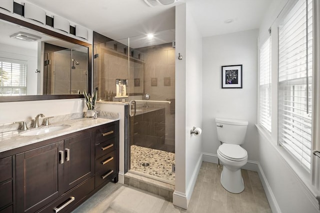 bathroom with toilet, a shower stall, baseboards, and vanity