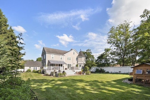 rear view of property with fence, a lawn, and an outbuilding