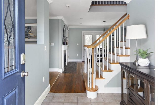 tiled entryway with baseboards, a fireplace, stairway, and crown molding