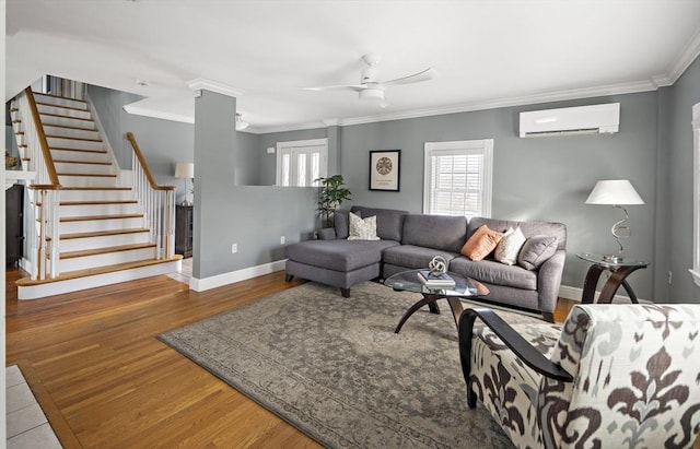 living room featuring baseboards, stairway, ornamental molding, wood finished floors, and a wall mounted air conditioner