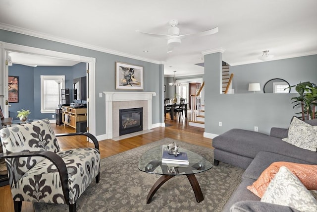 living room featuring stairs, plenty of natural light, wood finished floors, and crown molding