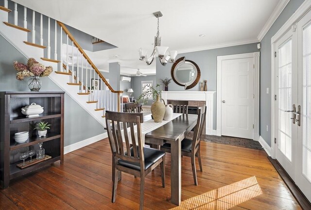 dining room featuring french doors, crown molding, stairway, an inviting chandelier, and hardwood / wood-style flooring