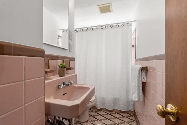 full bath with visible vents, tile patterned flooring, a wainscoted wall, and tile walls