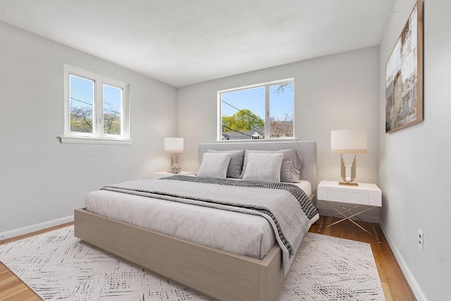 bedroom with baseboards, wood finished floors, and multiple windows