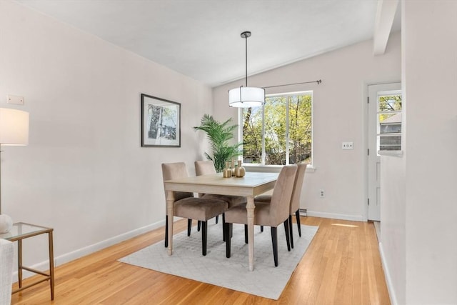 dining room featuring light wood-style floors, baseboards, and lofted ceiling