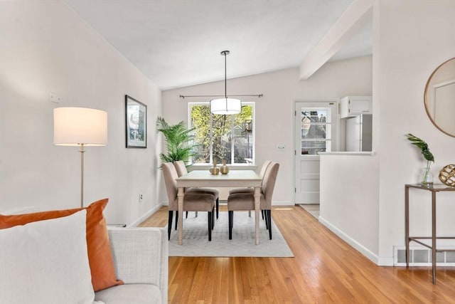 dining space with baseboards, vaulted ceiling, and light wood-style floors