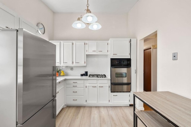 kitchen featuring appliances with stainless steel finishes, an inviting chandelier, light countertops, white cabinetry, and a warming drawer
