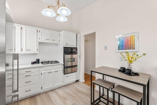 kitchen featuring light countertops, a chandelier, stainless steel appliances, backsplash, and a warming drawer