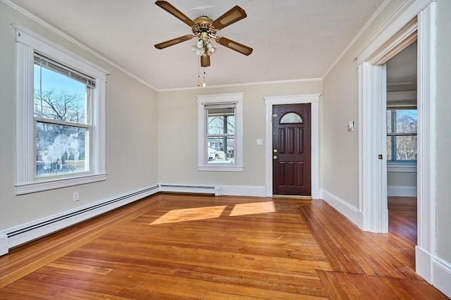 entrance foyer with baseboard heating, plenty of natural light, wood finished floors, and ornamental molding