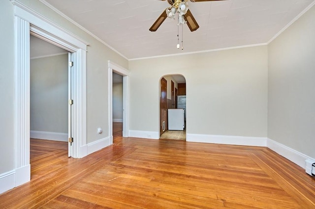 spare room featuring baseboards, arched walkways, ceiling fan, ornamental molding, and light wood-style floors