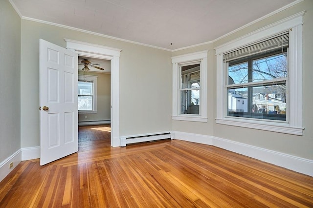 empty room with ornamental molding, hardwood / wood-style floors, baseboards, and a baseboard radiator