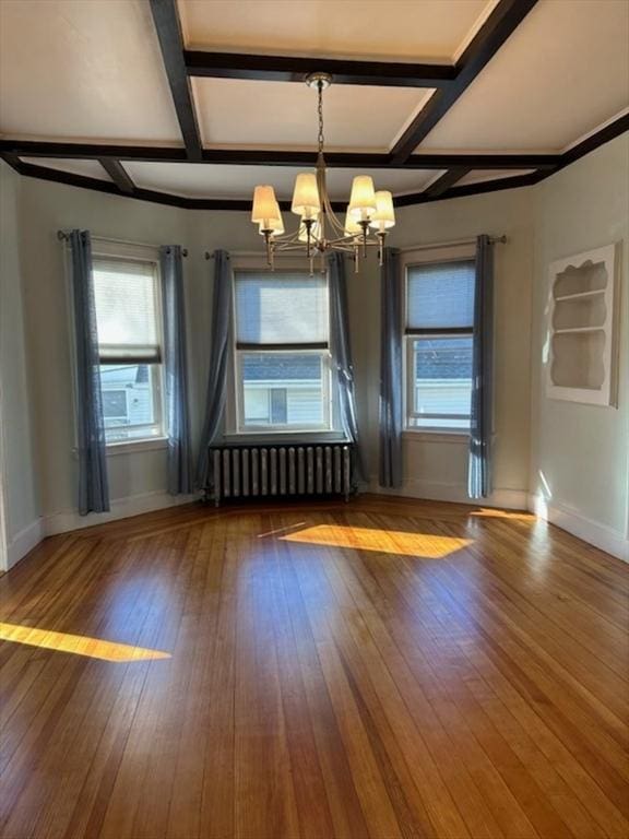 interior space featuring hardwood / wood-style flooring, radiator heating unit, coffered ceiling, and an inviting chandelier