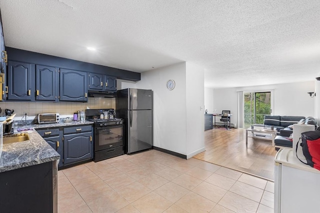 24 Inman St Unit 23, Lawrence, MA 01843 - kitchen featuring black gas range, freestanding refrigerator, under cabinet range hood, open floor plan, and tasteful backsplash