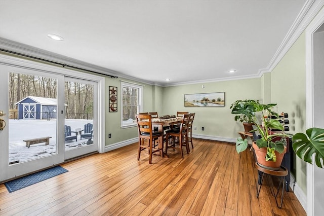 dining area with crown molding, a baseboard heating unit, and light wood-type flooring