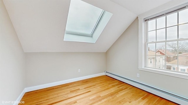 bonus room featuring wood-type flooring, vaulted ceiling with skylight, and a baseboard heating unit