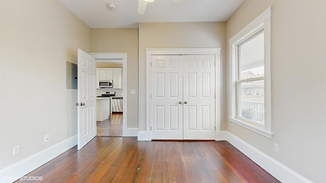 unfurnished bedroom featuring dark hardwood / wood-style floors, electric panel, a closet, and ceiling fan